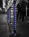Queue management system with blue posts and black stands on a city street at night.