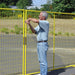 Man securing a yellow metal fence in an outdoor setting